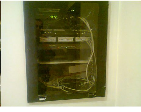 Rack de comunicaciones montado en pared con equipamiento de transmisión ordenado